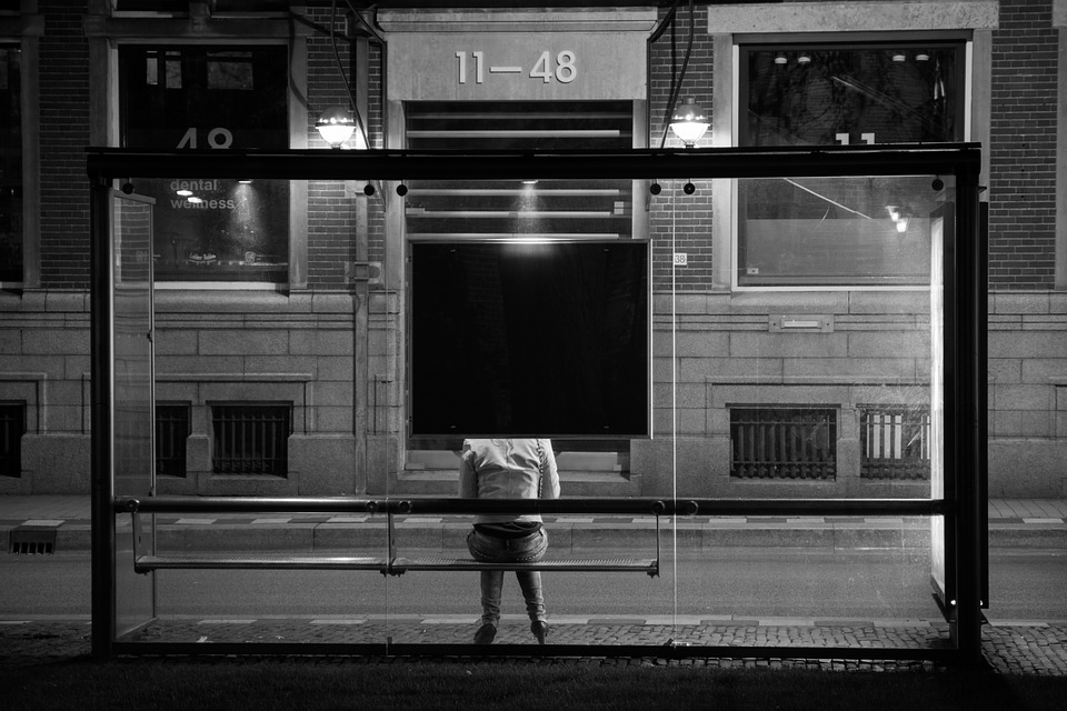 passagier zit op een bankje in de bushalte bij avond
